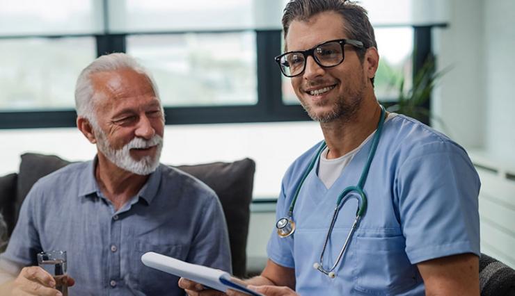 Um idoso e um médico sorrindo, um do lado do outro